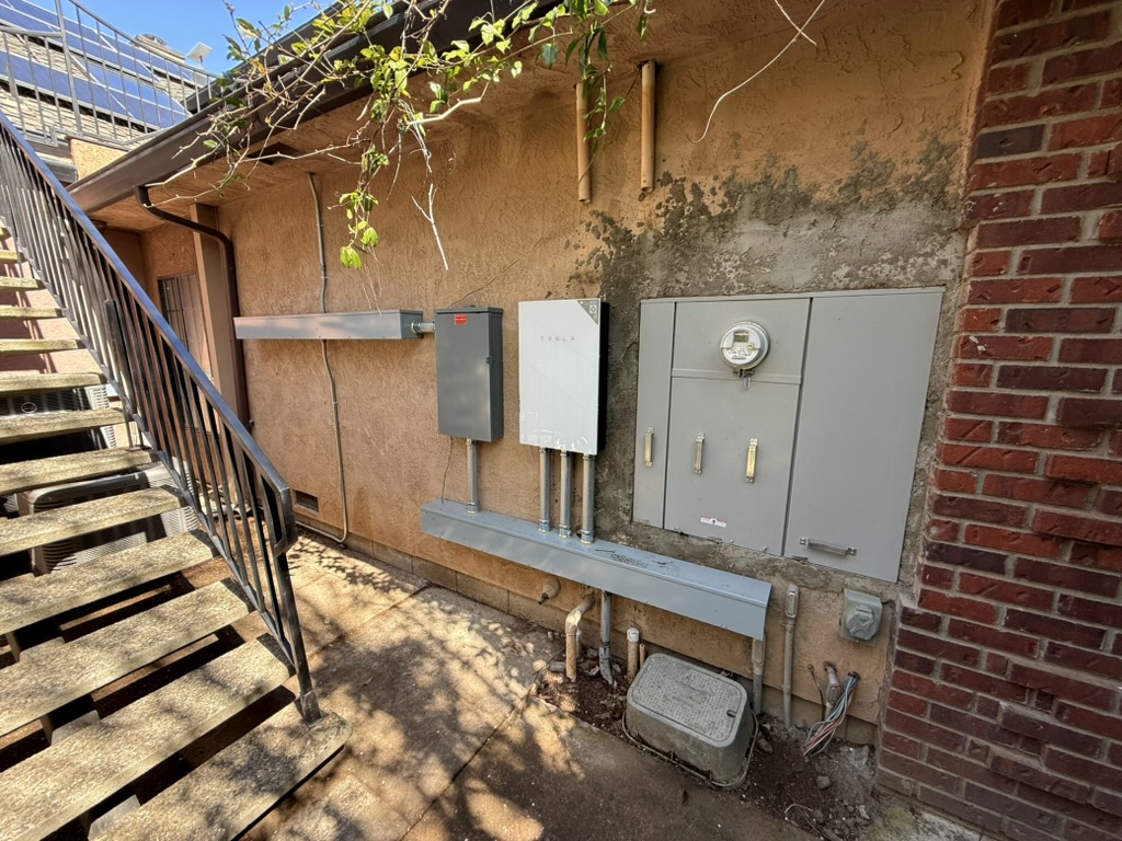 Coordinated Tesla equipment, main panel, wireway, and conduit on the side of an Acampo home