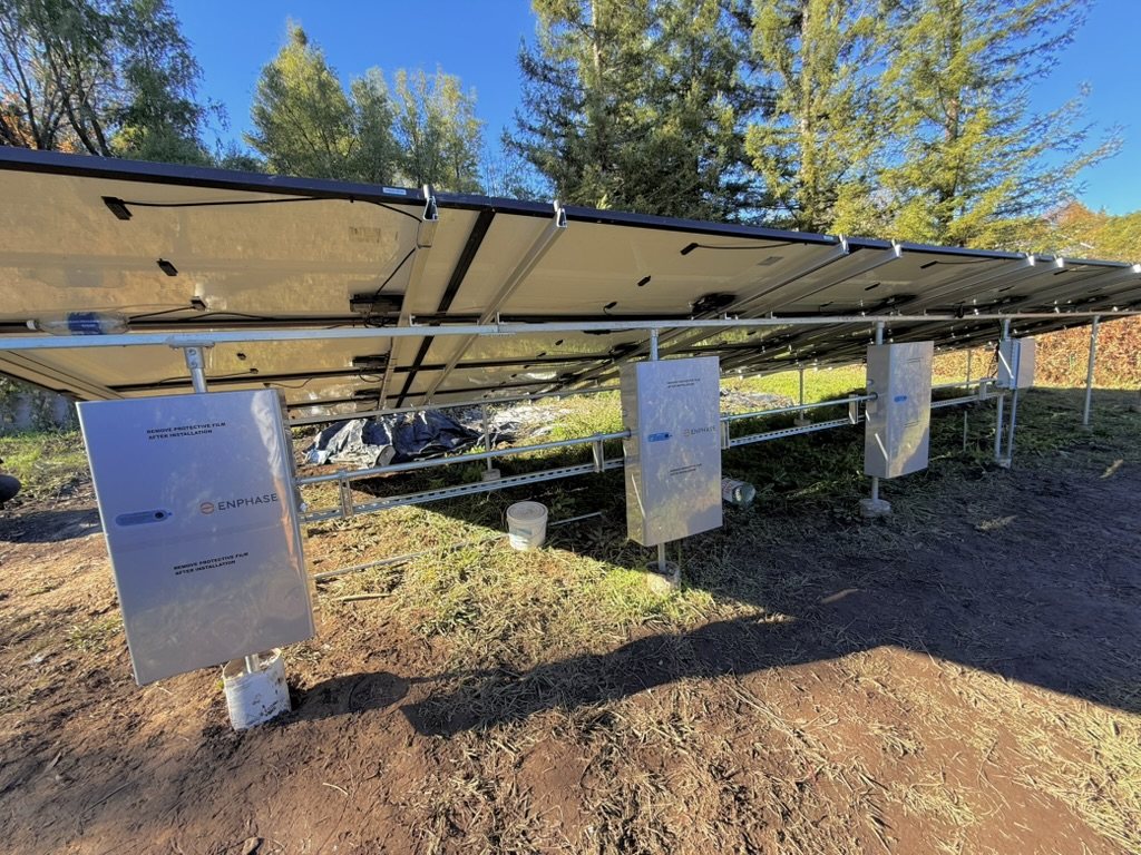 Ground-mounted solar array with Enphase equipment installed beneath the panels